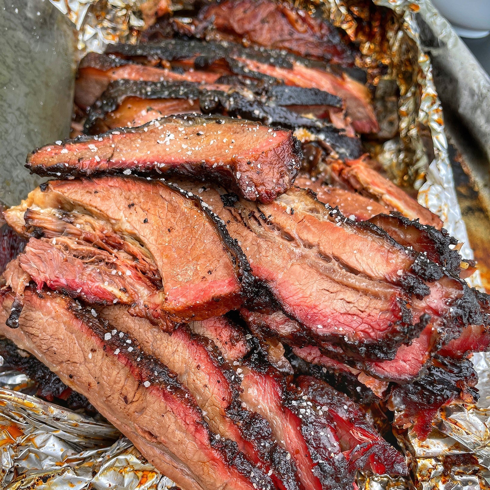 Sliced smoked meat on a tray with foil