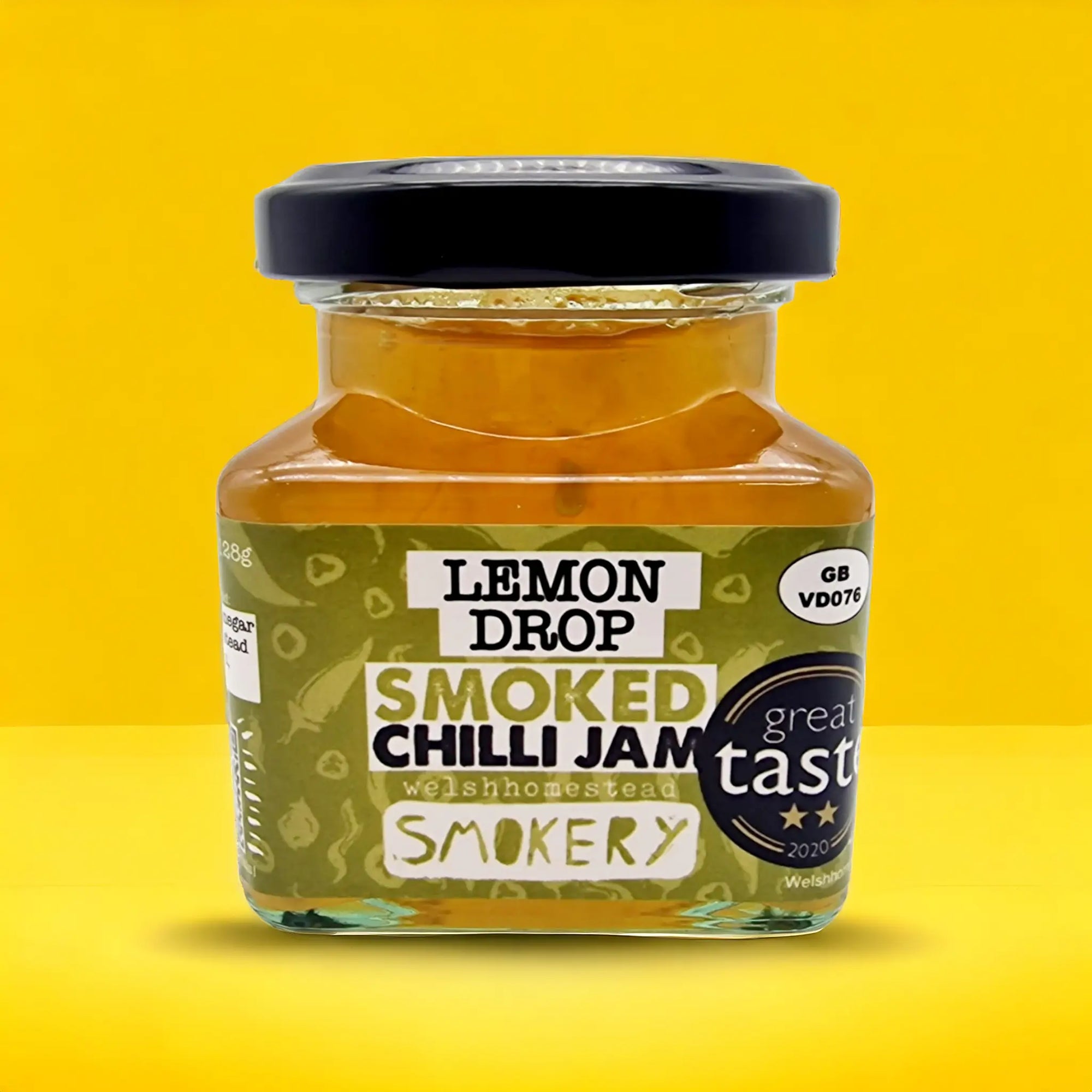 Jar of Lemon Drop Smoked Chilli Jam with a black lid on a yellow background