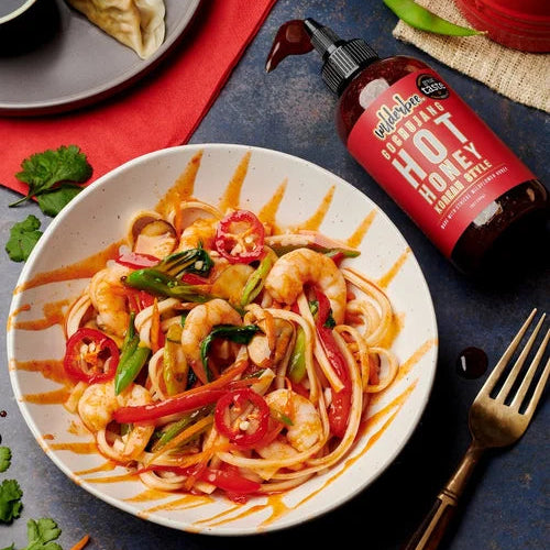 WilderBee hot honey drizzled onto a stir fry with a bottle of WilderBee hot honey next to the bowl