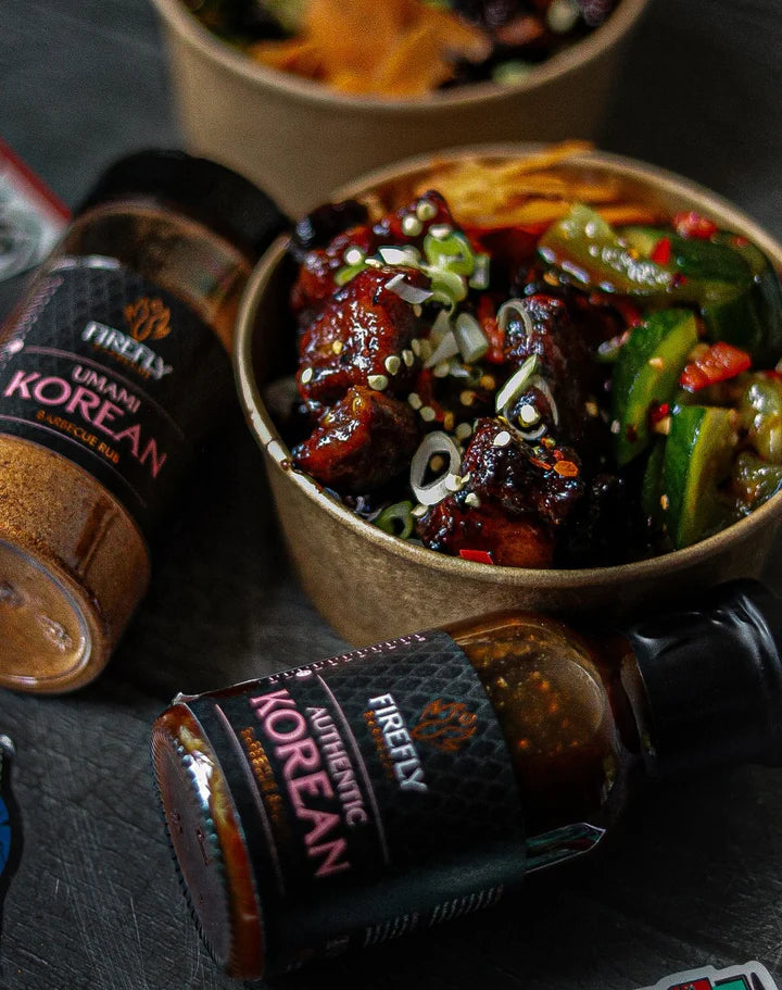 Bowl of Korean cuisine with Firefly Korean sauce and seasoning bottles on a dark surface
