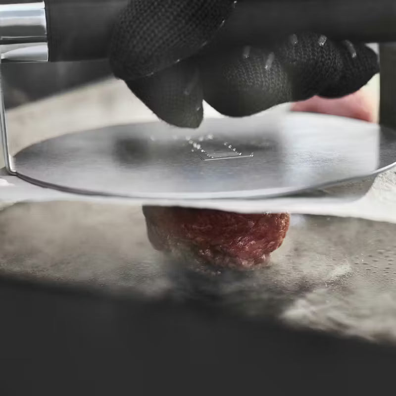 Weber Griddle Smashed Burger Press being used to press a burger into shape against a griddle