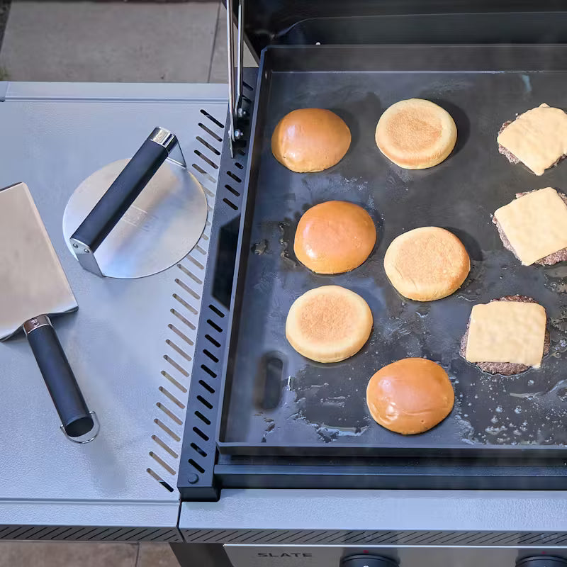 Weber Griddle Smashed Burger Press and Spatula resting on the side of a slate