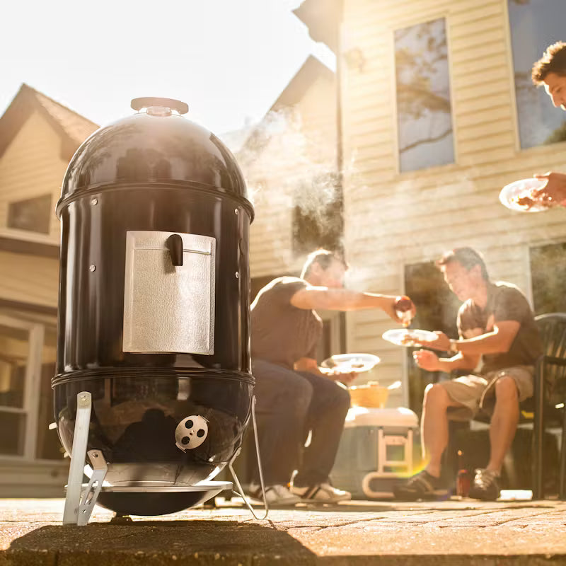 Weber Smokey Mountain Cooker and Smoker with people sitting around it on a patio