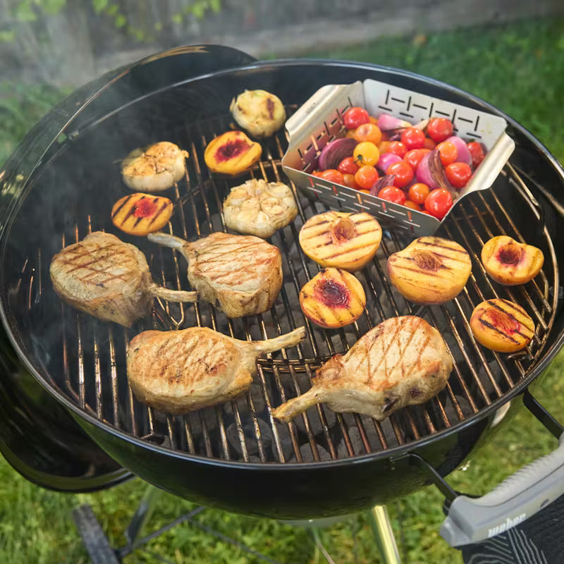 Weber Charcoal Grill with pork chops and vegetables cooking outdoors