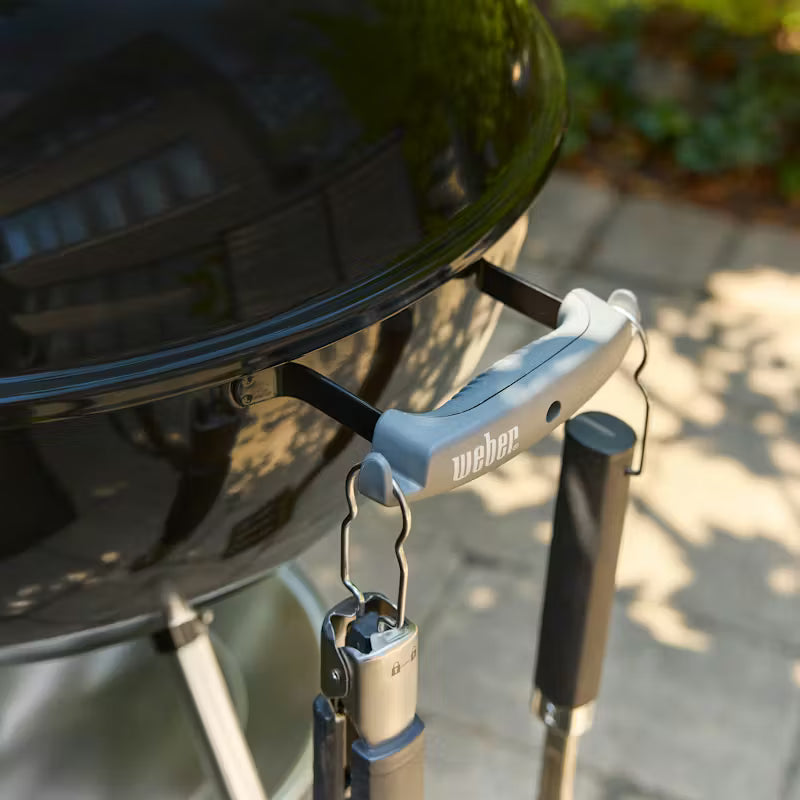 Weber grill lid lifter attached to a Weber grill on a patio