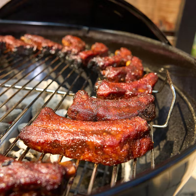 Barbecued ribs on a Weber Charcoal grill with a close-up view